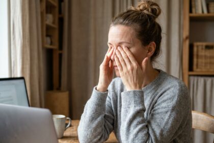 Femme soulagée de la sécheresse oculaire en se massant les yeux fermés devant son bureau